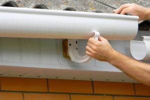 Contractor installing plastic roof gutter