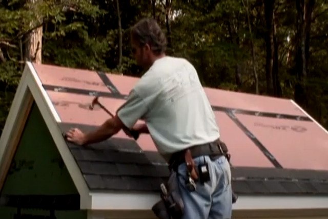 Roofing worker installing shingles.