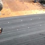 Roofing worker installing insulation pad on a roof.